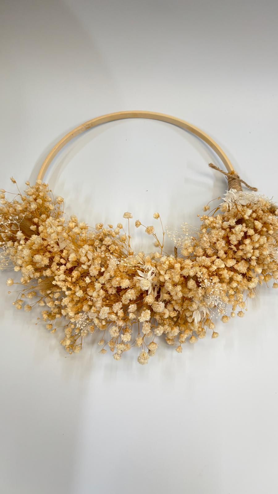 Decorative wreath with dried flowers on a plain background